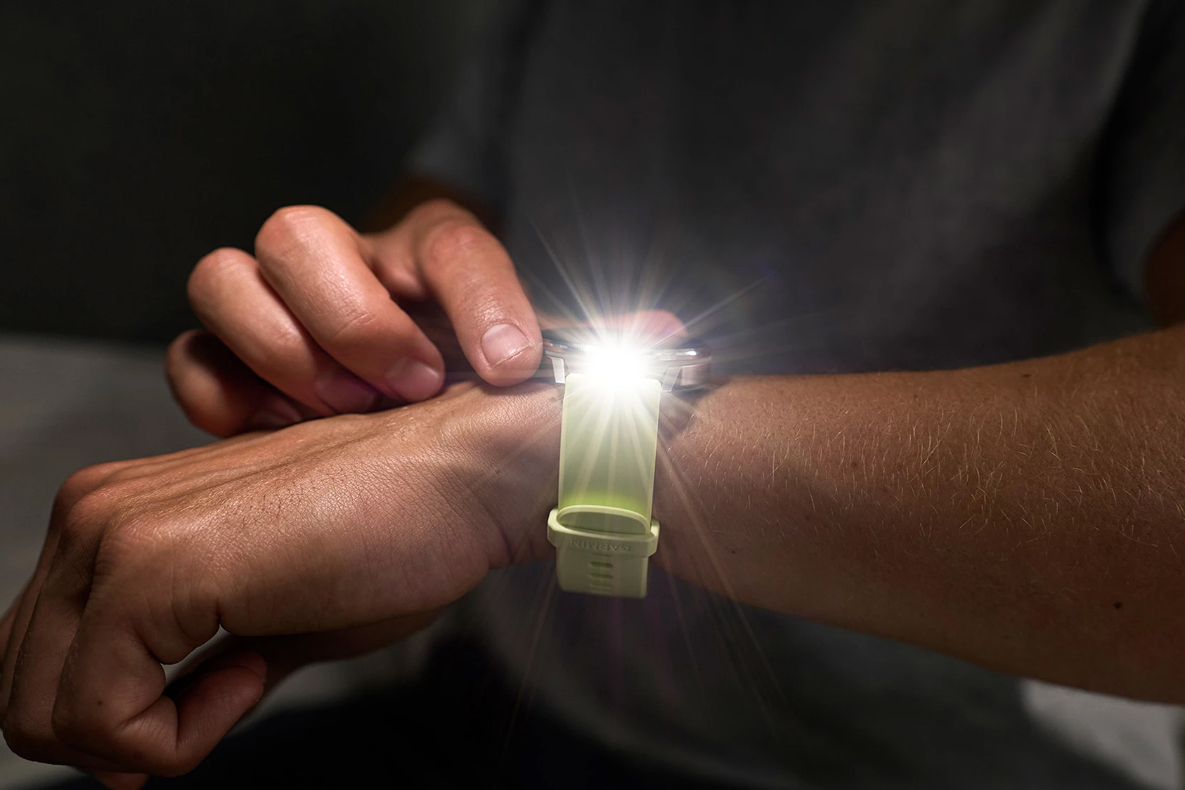A person uses the LED flashlight feature on the Garmin Venu 4 smartwatch.