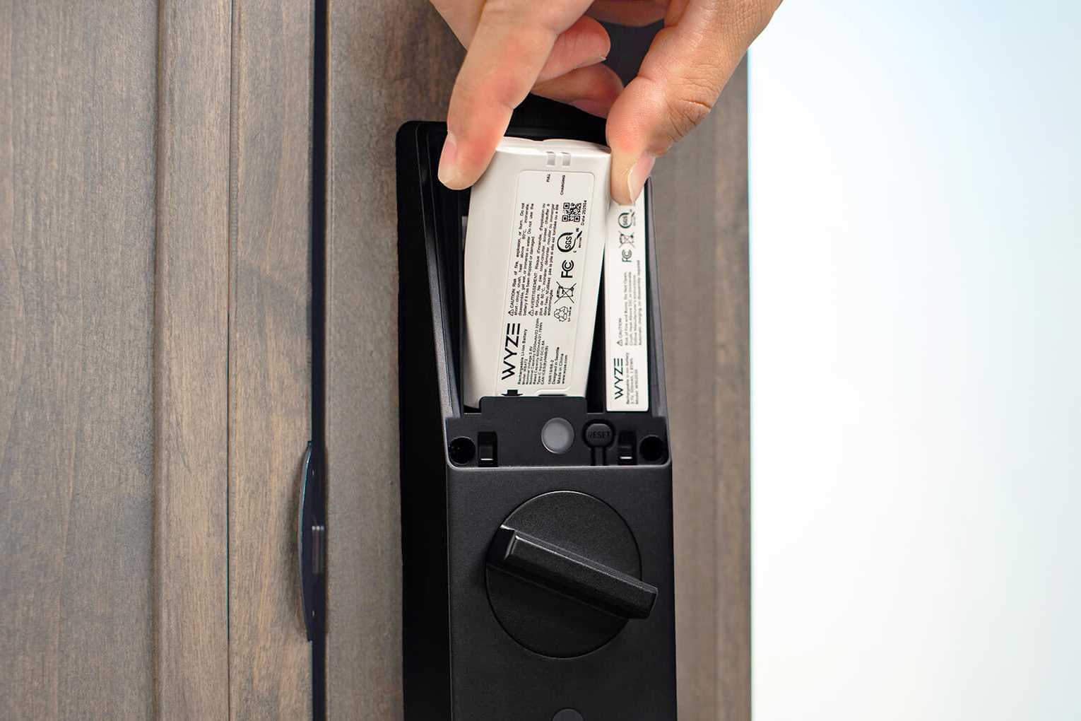 A person removes one of the Wyze Palm Lock’s two rechargeable batteries.