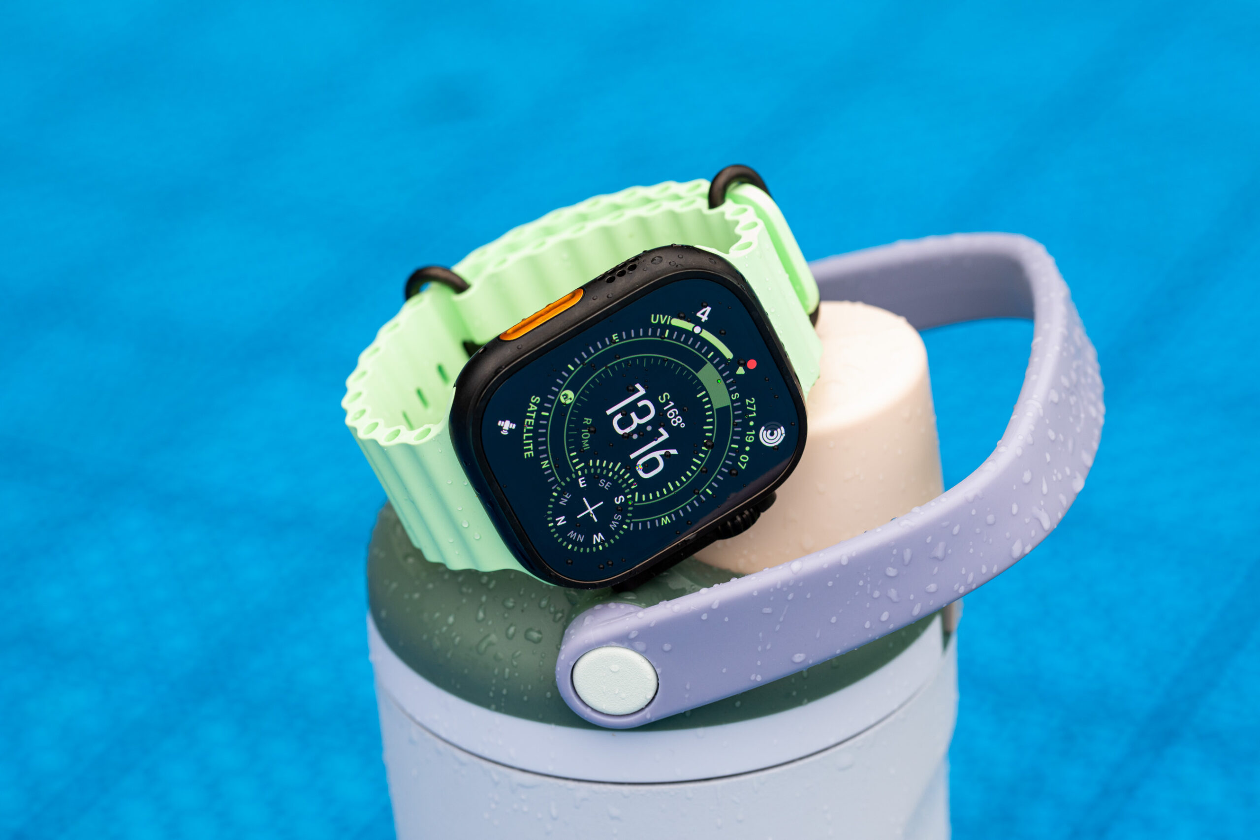 Apple Watch Ultra 3 with rain droplets on the screen atop a water bottle.