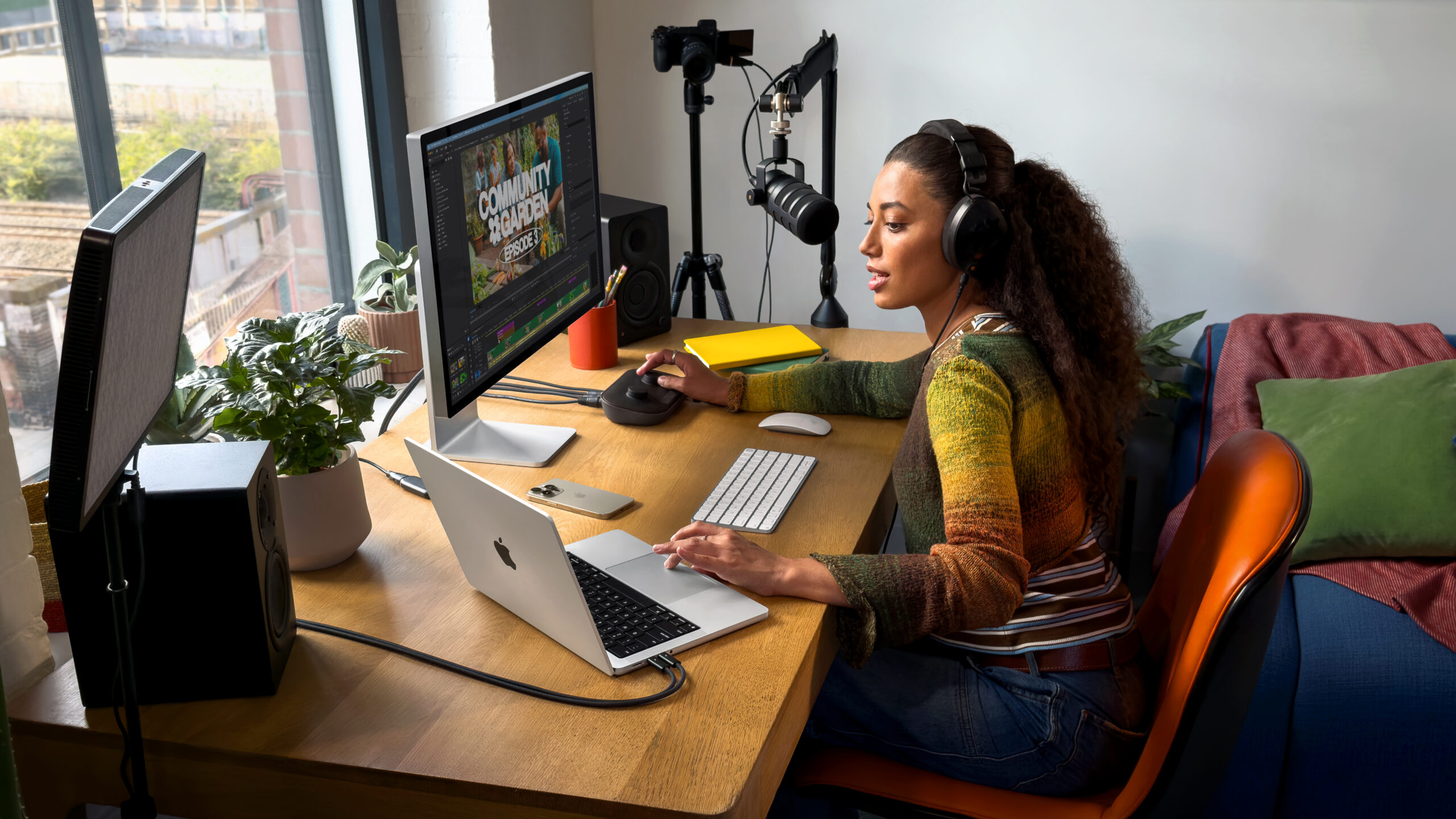 A woman sitting at a desk using an M5 MacBook Pro connected to a pair of monitors. 