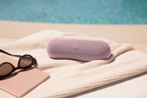 A marketing of the pink Beats Pill speaker on a beach.