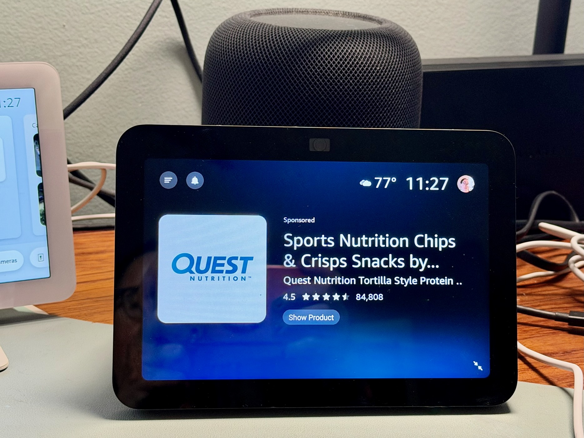 A smart display on a cluttered desk showing an ad for a Quest snack.