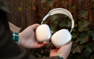 Hands holding the silver Apple AirPods Max.