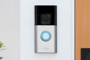 The Ring Battery Doorbell Plus mounted onto a wall next to a door.