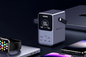 Ugreen Portable Charger (48K, 300W, 6-Port) on a table next to two MacBooks, and an iPhone, Android phone, and Apple Watch.