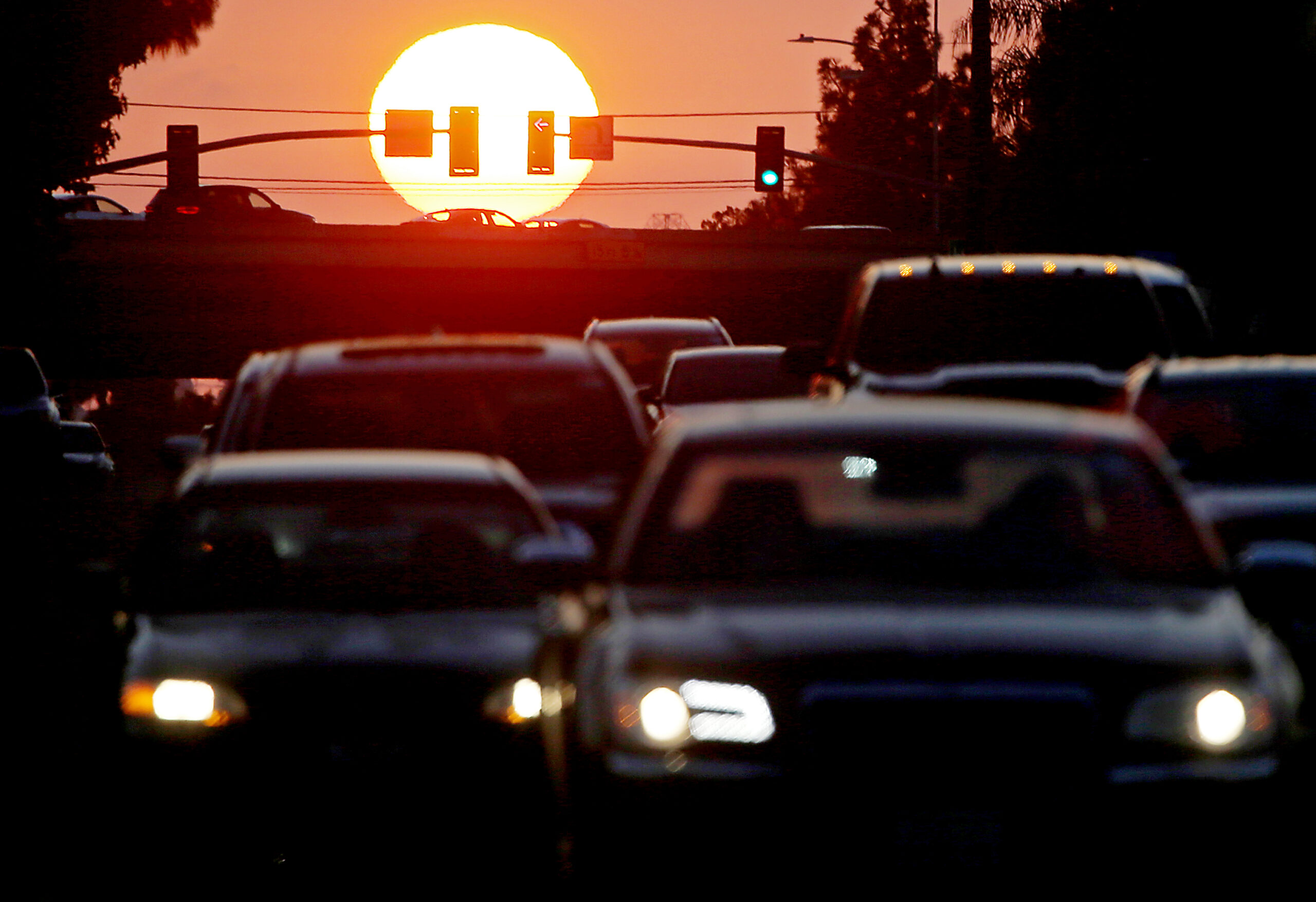 Vehicle traffic seen under a setting sun.