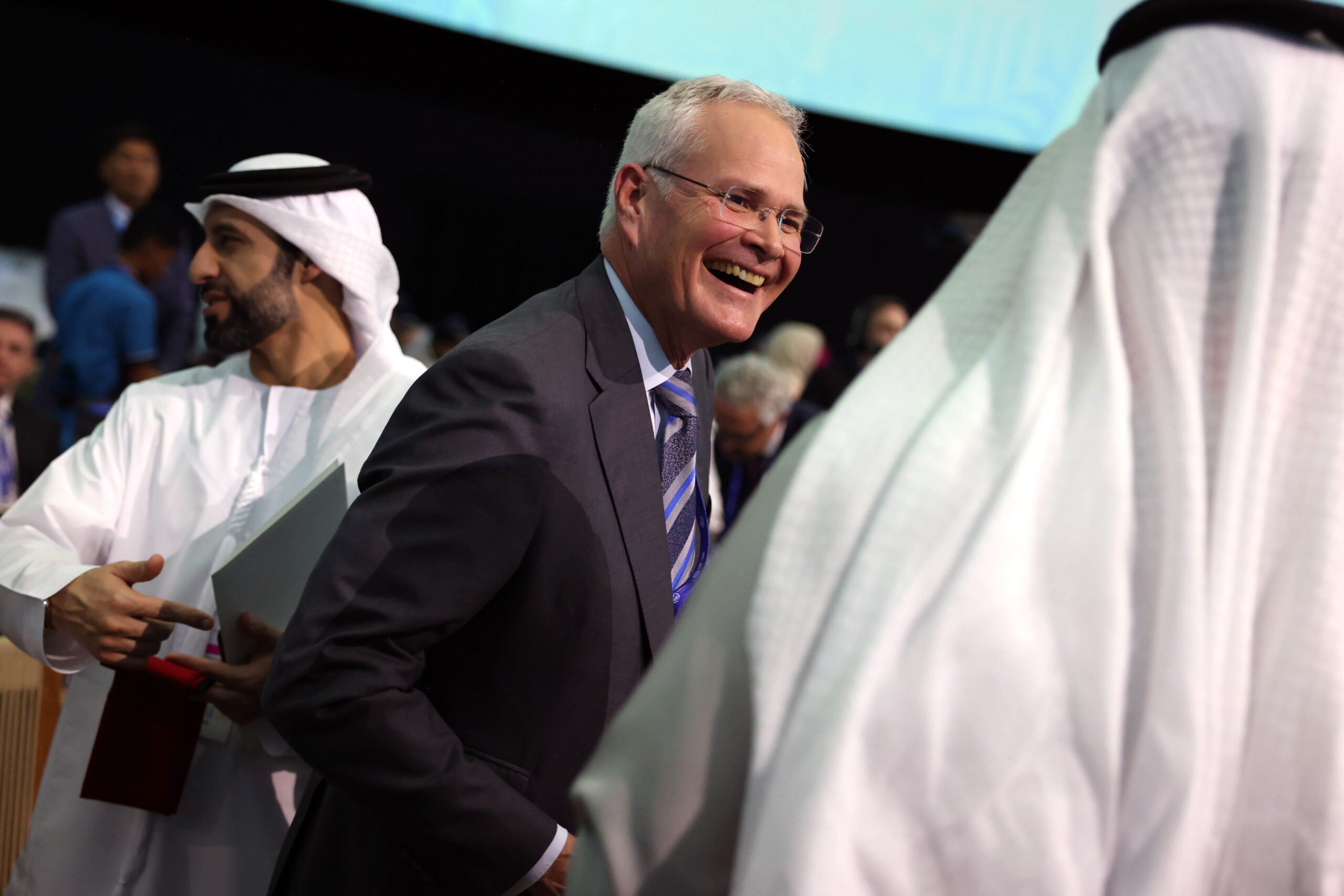A man in a suit smiling at a conference.