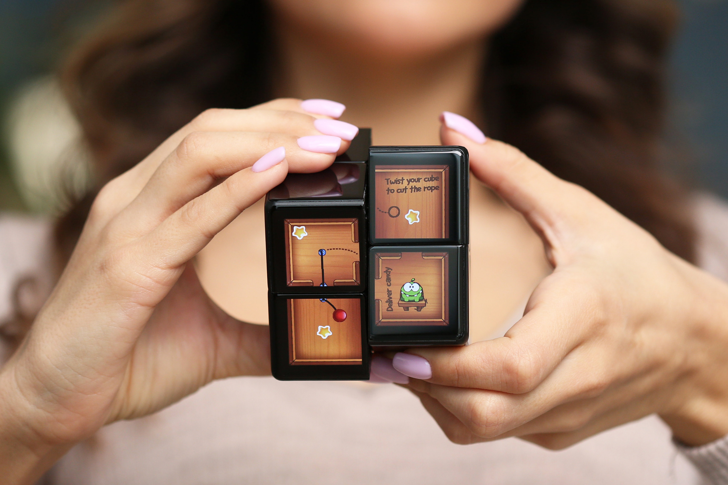 A person twists the Rubik’s WOWCube while playing a version of Cut the Rope.