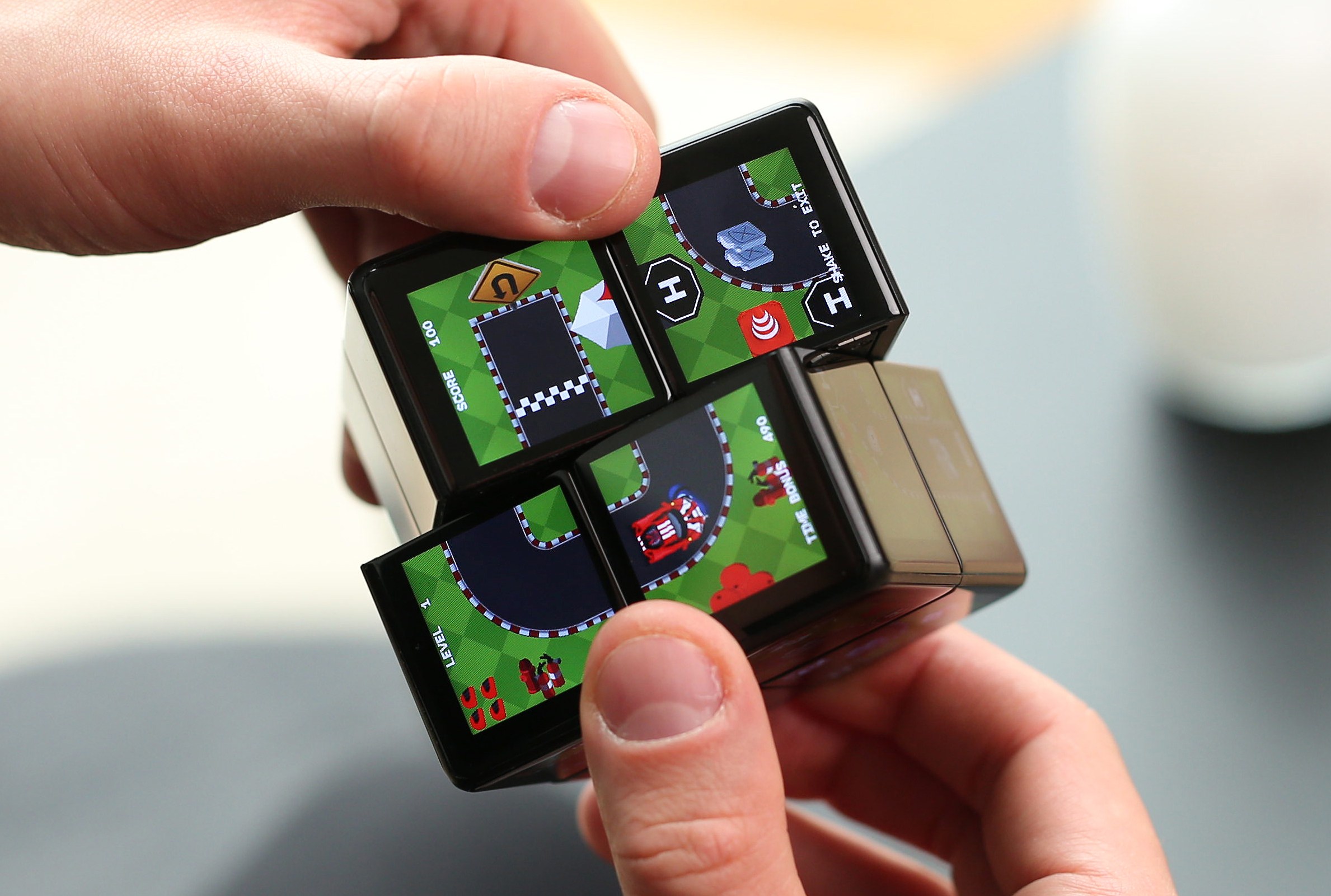 A person spins the Rubik’s WOWCube while playing a racing game.