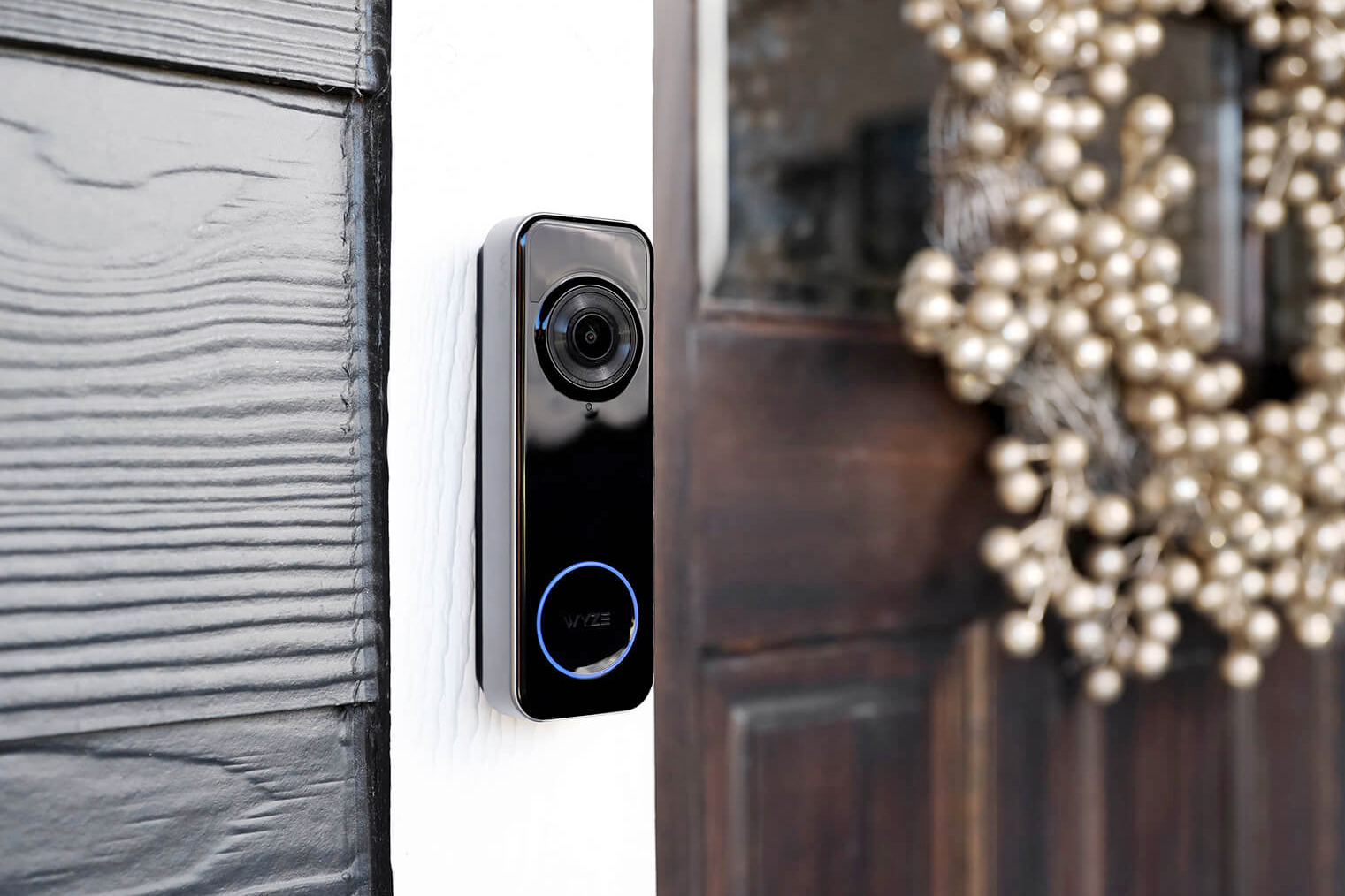 A Wyze battery-powered doorbell attached to the frame next to a front door.