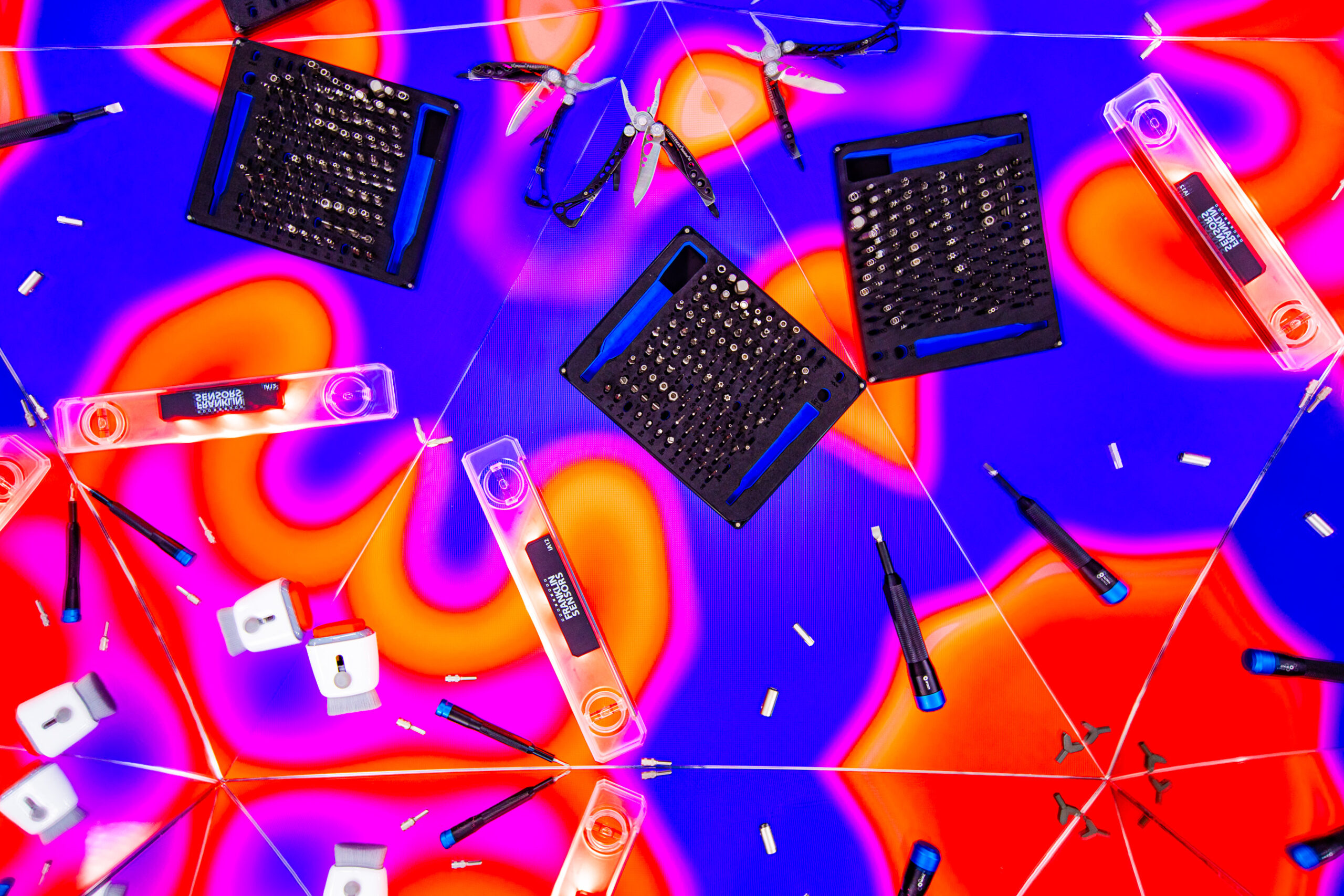 An image with a kaleidoscopic effect centered on various tools, from iFixit’s tool kit to a level that has a light on it.