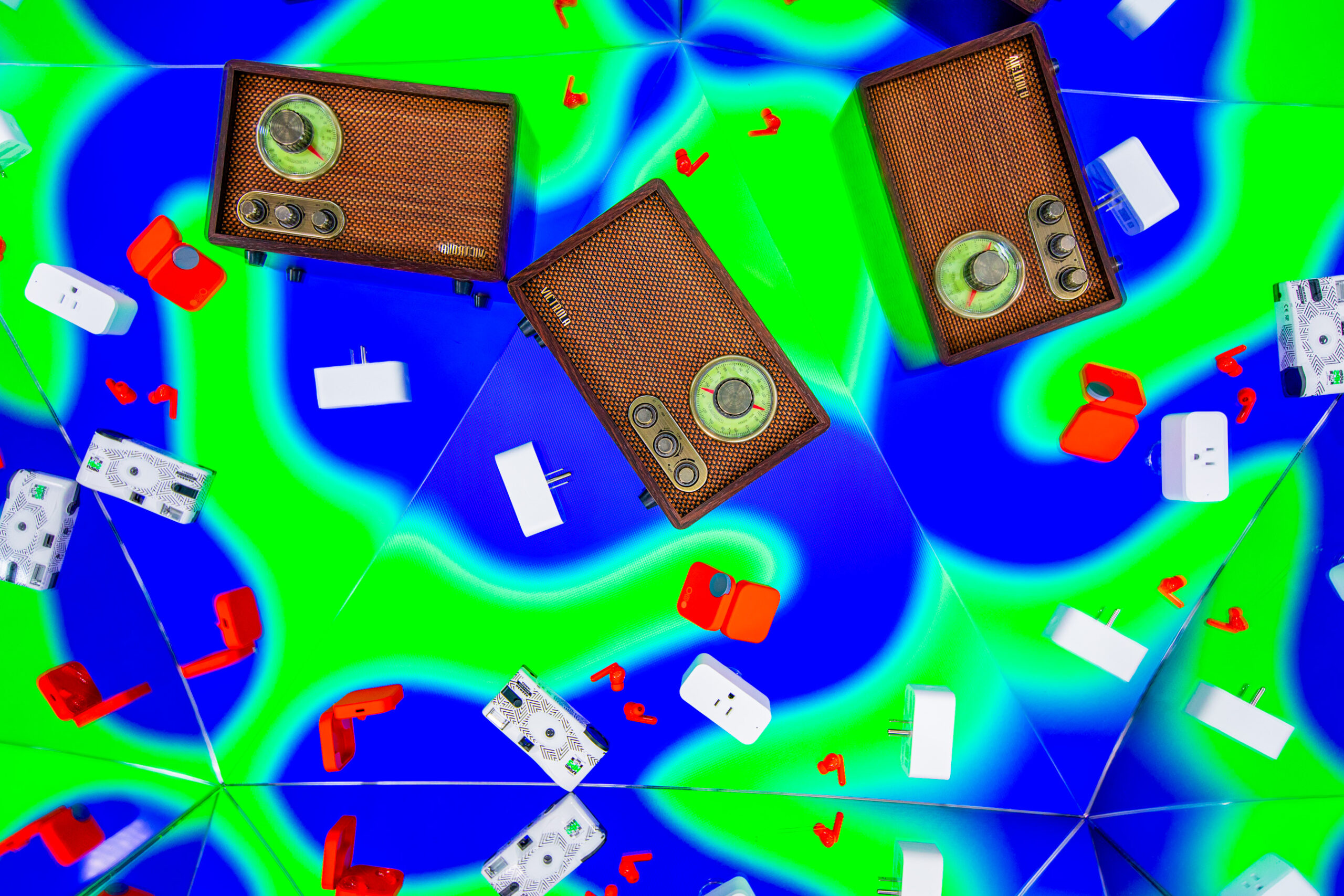 An image with a kaleidoscopic effect centered on various gadgets, from the CMF Buds Pro 2 and the Victrola Willow Retro Radio.