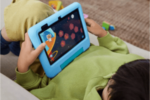 A kid holding the Amazon Fire 7 Kids tablet in blue.
