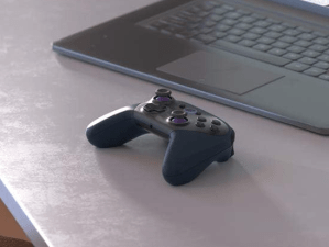 The Amazon Luna wireless controller sitting on a table next to a laptop.