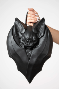 Hand holding handbag in the shape of a bat with its wings folded