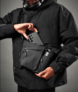 Person putting phone into black slink that also has a water bottle and several pockets