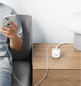 Anker cube power strip on table in between a person with a phone and a computer