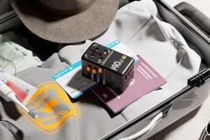 Tessan's Universal Travel Adapter on top of a passport and clothes in a suitcase.