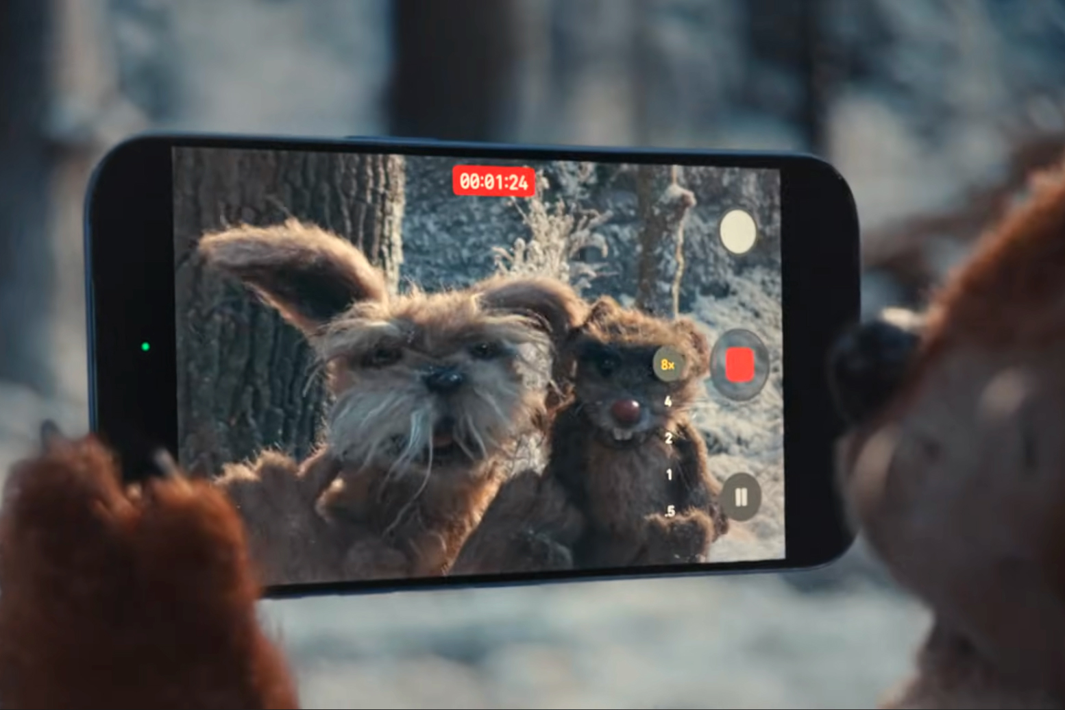 A screenshot of a puppet woodland creature using an iPhone 17 Pro to film other animals.