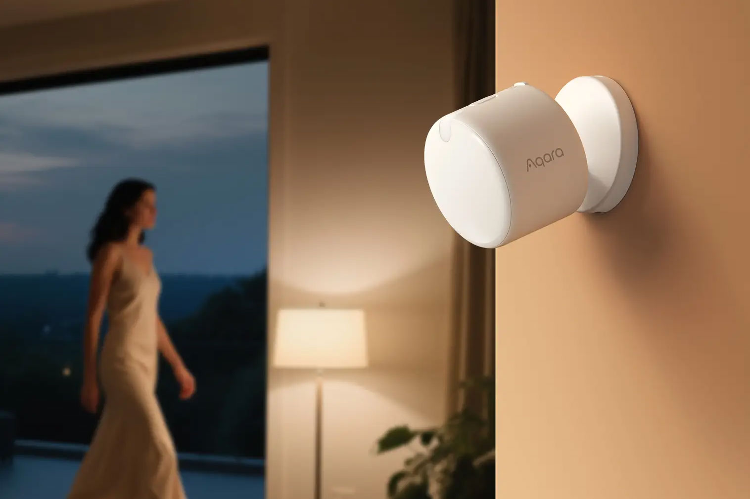 An Aqara presence sensor mounted to a wall while a person walks past in the distance.