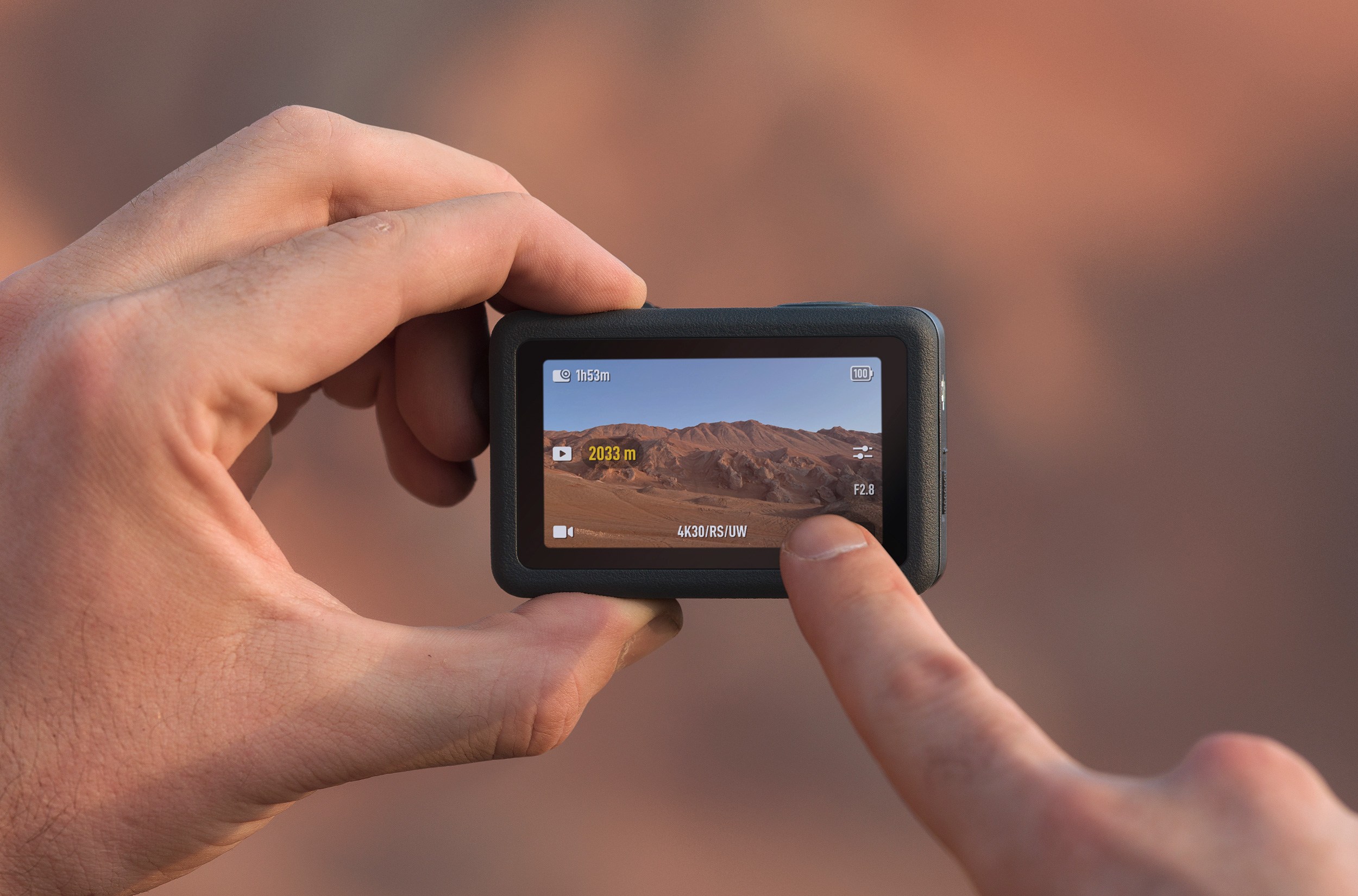 A person holds the DJI Osmo Action 6 and taps its rear touchscreen with a finger. A person holds the DJI Osmo Action 6 and taps its rear touchscreen with a finger.