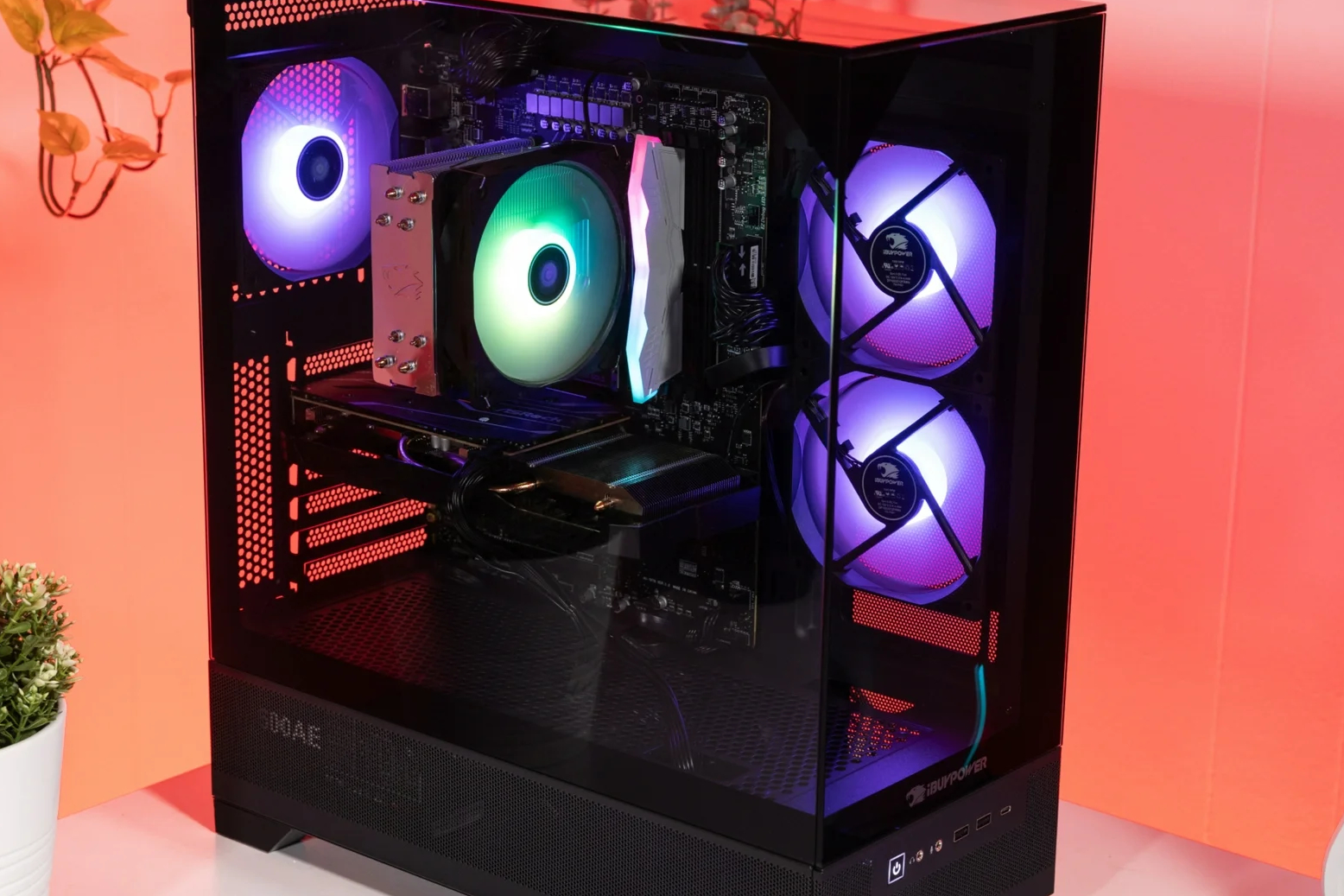 An image showing the iBuyPower Elevate SE pre-built gaming PC on a red background with its multicolor RGB fans spinning.