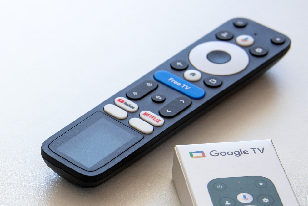 A Google TV reference remote with an integrated solar cell next to the remote’s packaging.