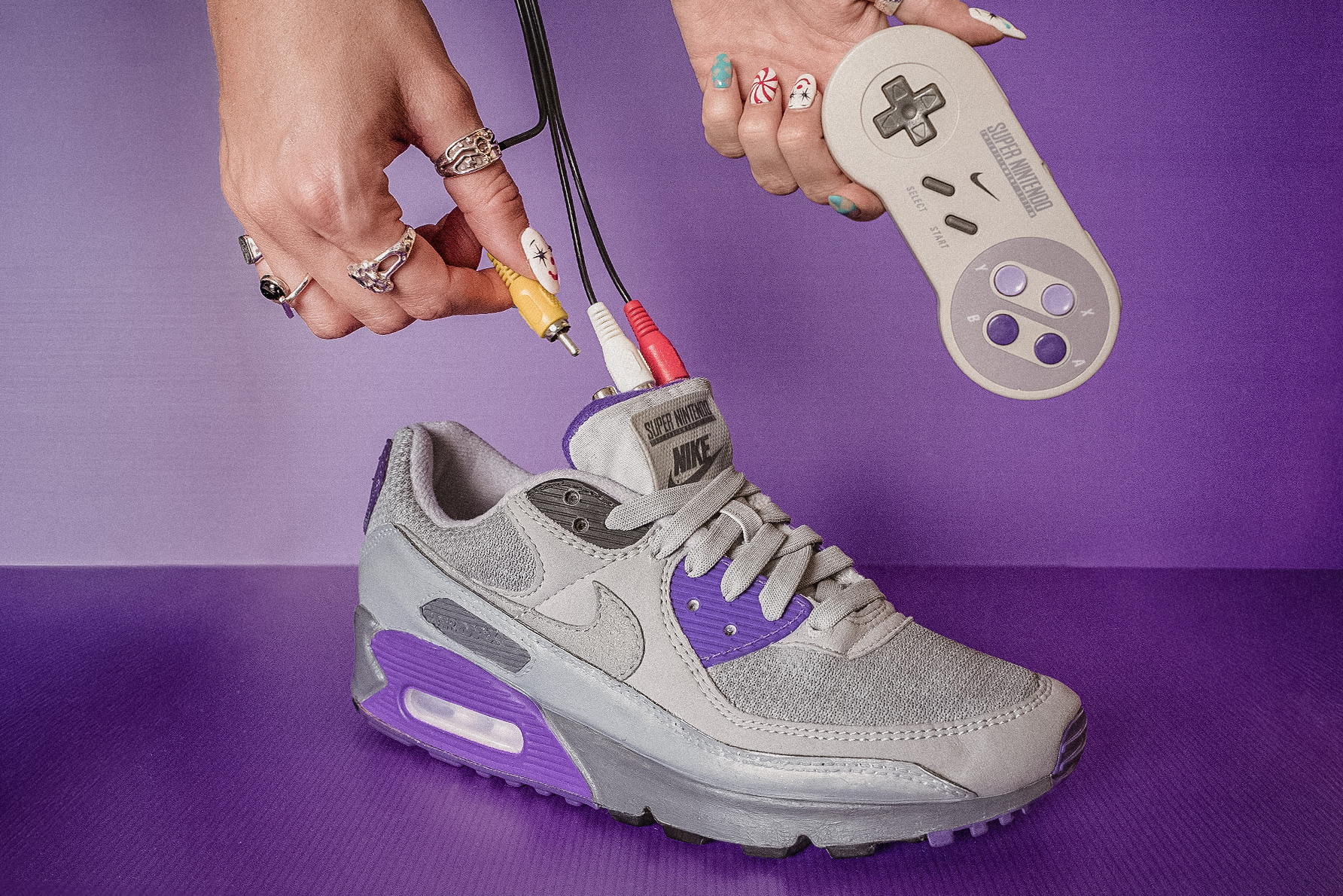 A person plugs RCA cables into Gustavo Bonzanini’s custom AIR SNES sneakers.