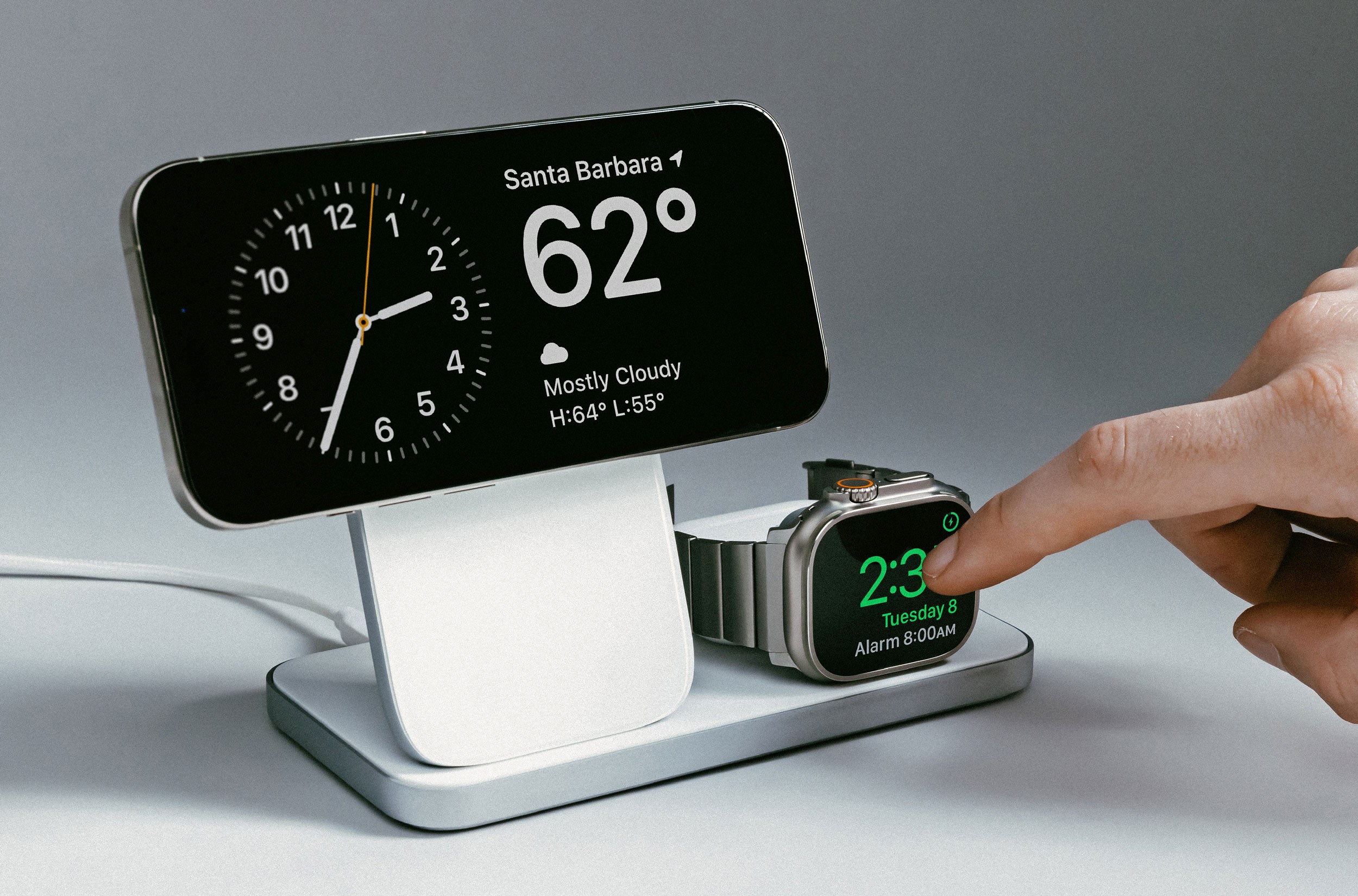 An iPhone, Apple Watch, and AirPods charging on Nomad’s Stand One Max charger.