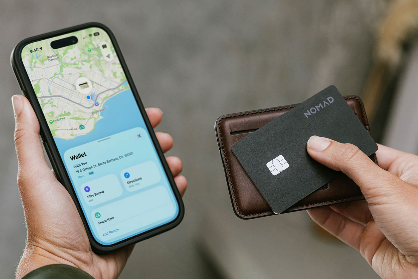 A person holds the Nomad Tracking Card pro against a wallet next to their iPhone.