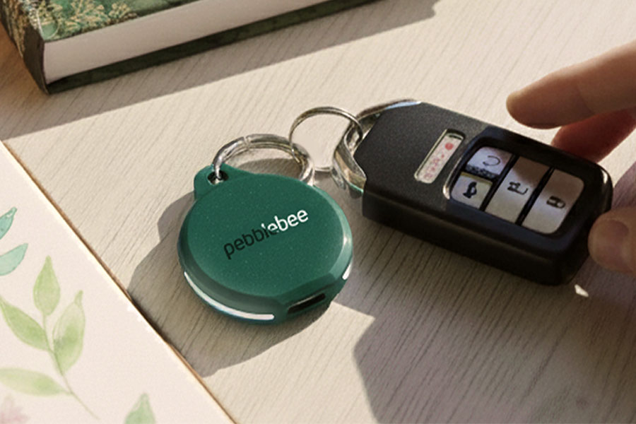 The Pebblebee Clip 5 tracker attached to a key fob on a wooden table.