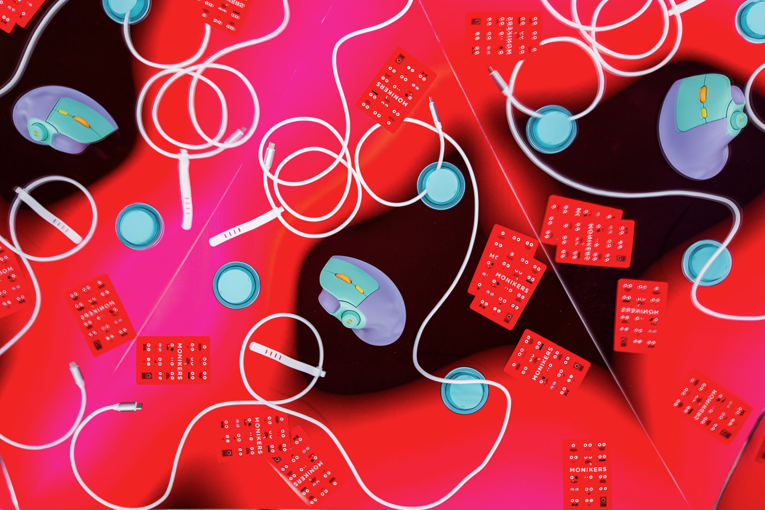 Various small tech items such as mice and cords against a red background.