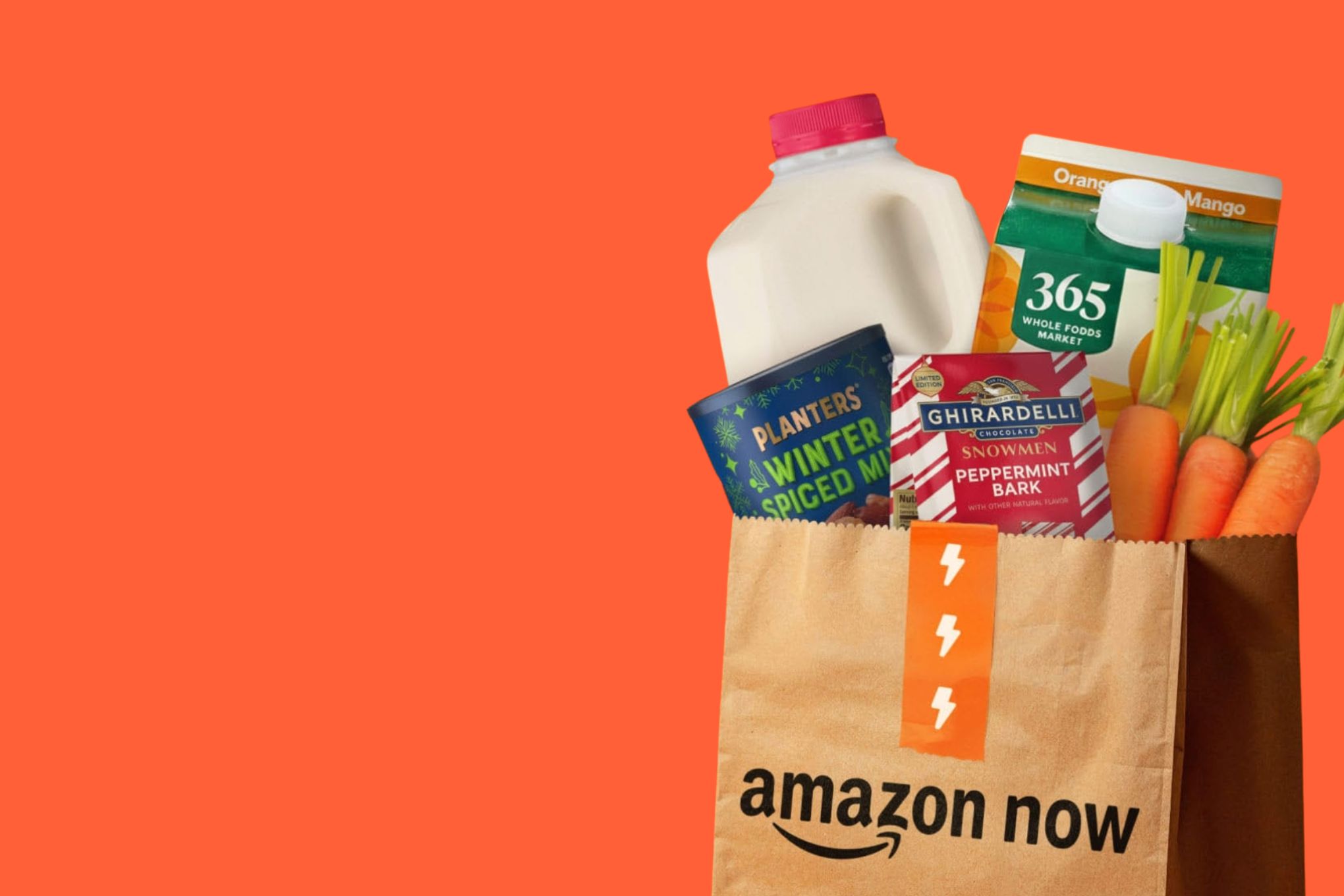 An Amazon Now shopping bag full of groceries, against a bright orange background.