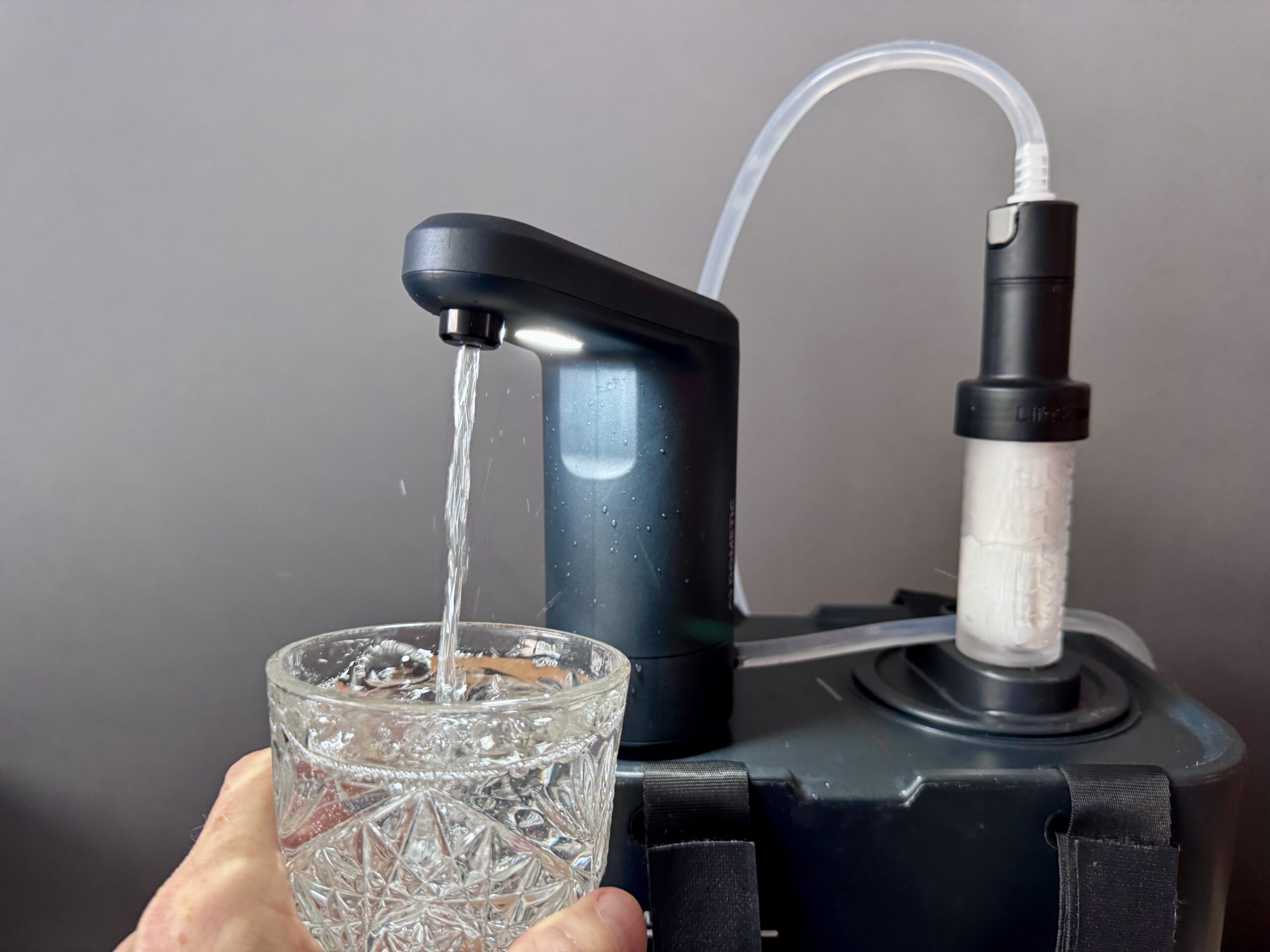 The Dometic Recon 360 Faucet sits on top of a Dometic Go Jug and pumps water into a glass through a LifeStraw filter.