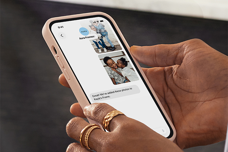 A person holds a smartphone showing images being sent through text messages.