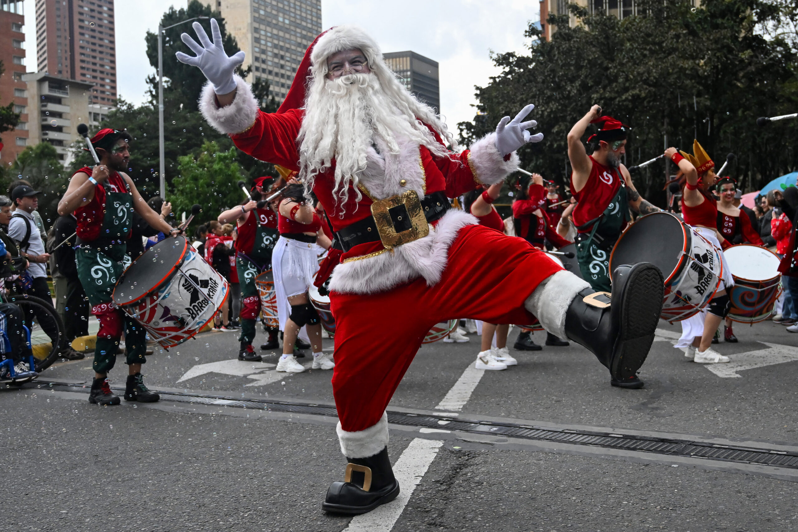 A man dressed as Santa Claus dancing at a parade.