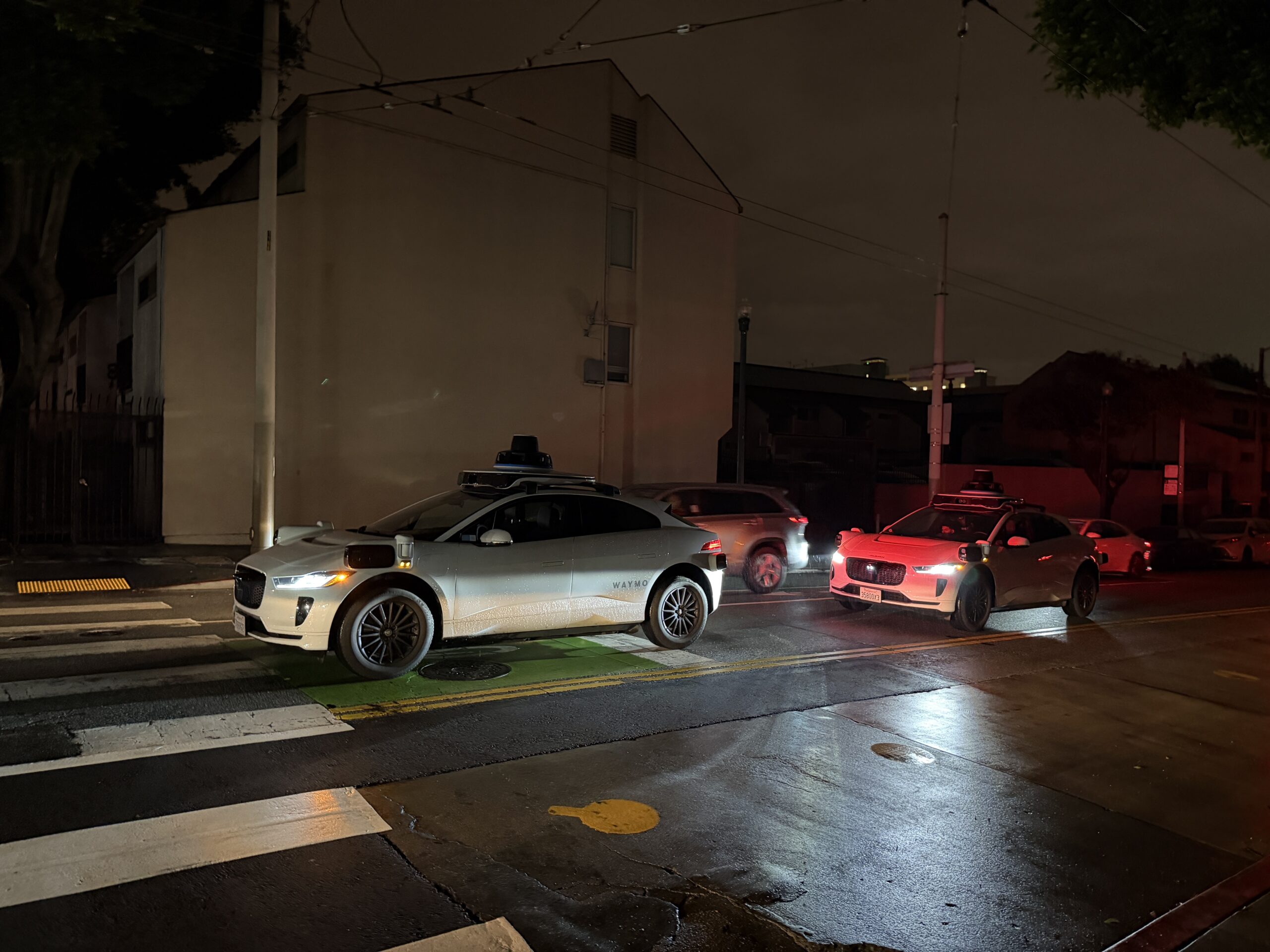 Two Waymo cars sit motionless in a San Francisco street on the evening, among darkened buildings during the power outage.