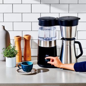 Person’s hand turning on an Oxo coffee maker