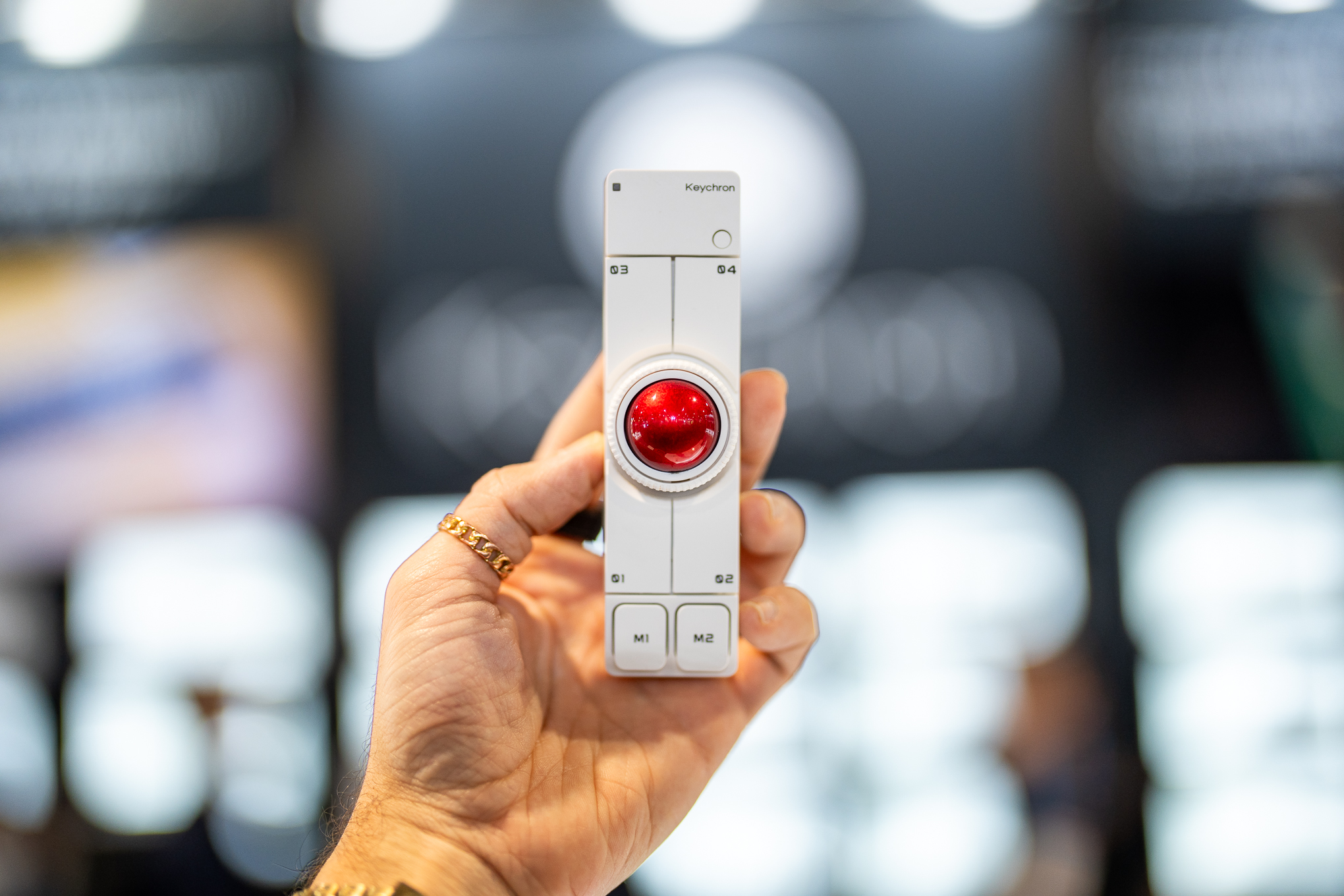 A hand holding up the white Keychron Nape Pro with its bright red trackball centered in the frame.