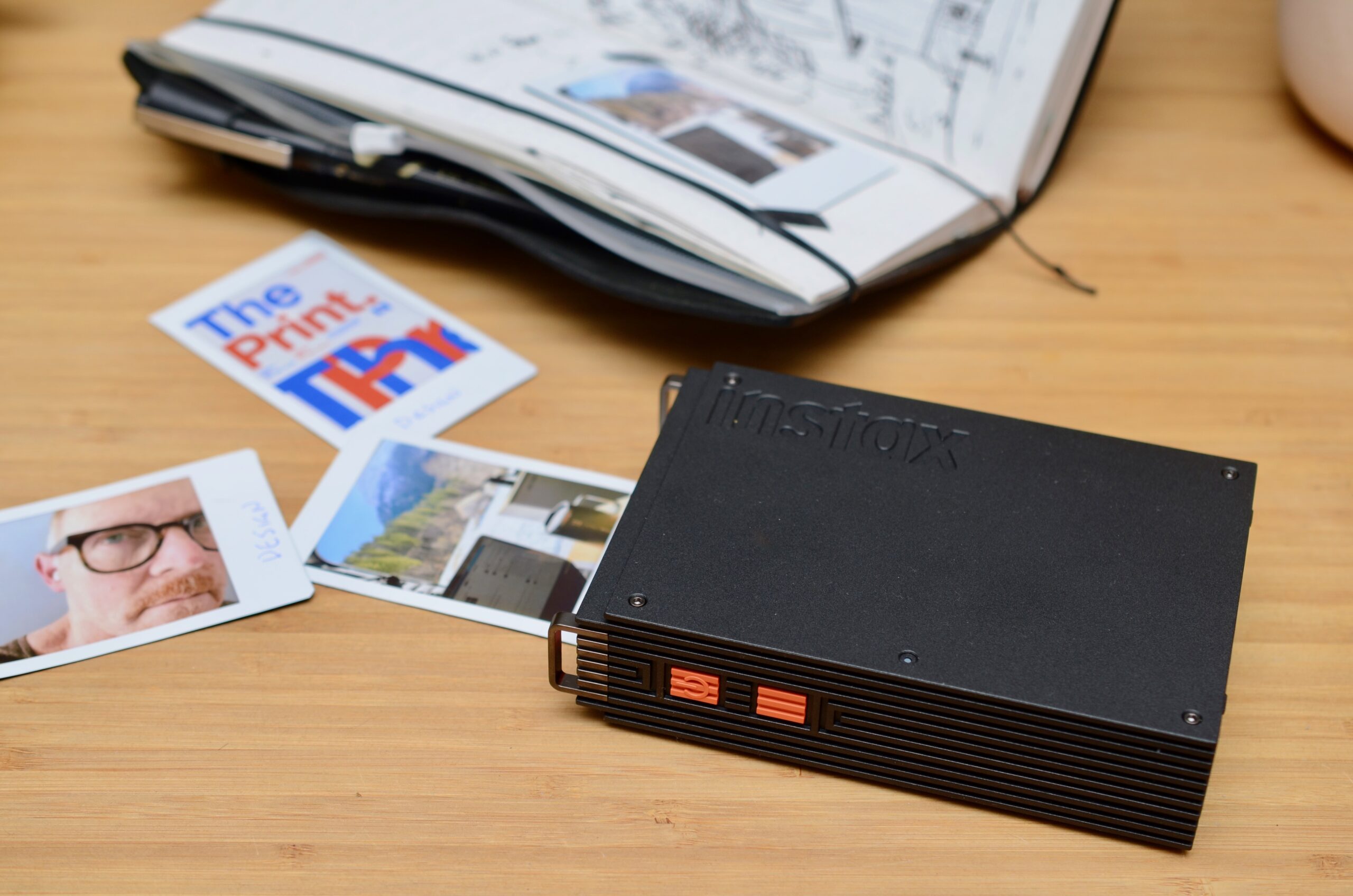 The Instax Mink Link+ next to three photos and an open journal.