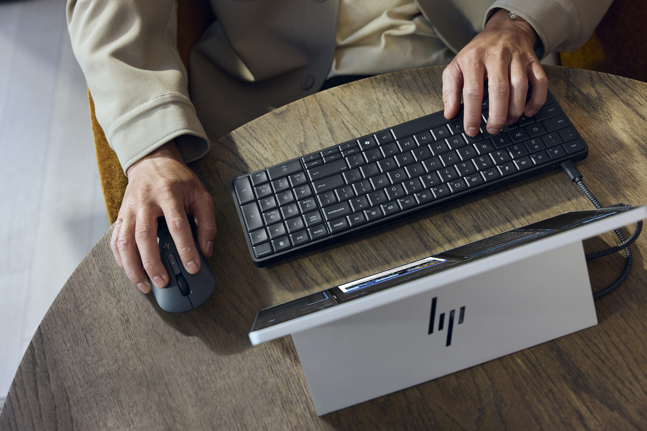 A person using an HP Eliteboard G1a keyboard / desktop computer plugged into a portable monitor with a kickstand.