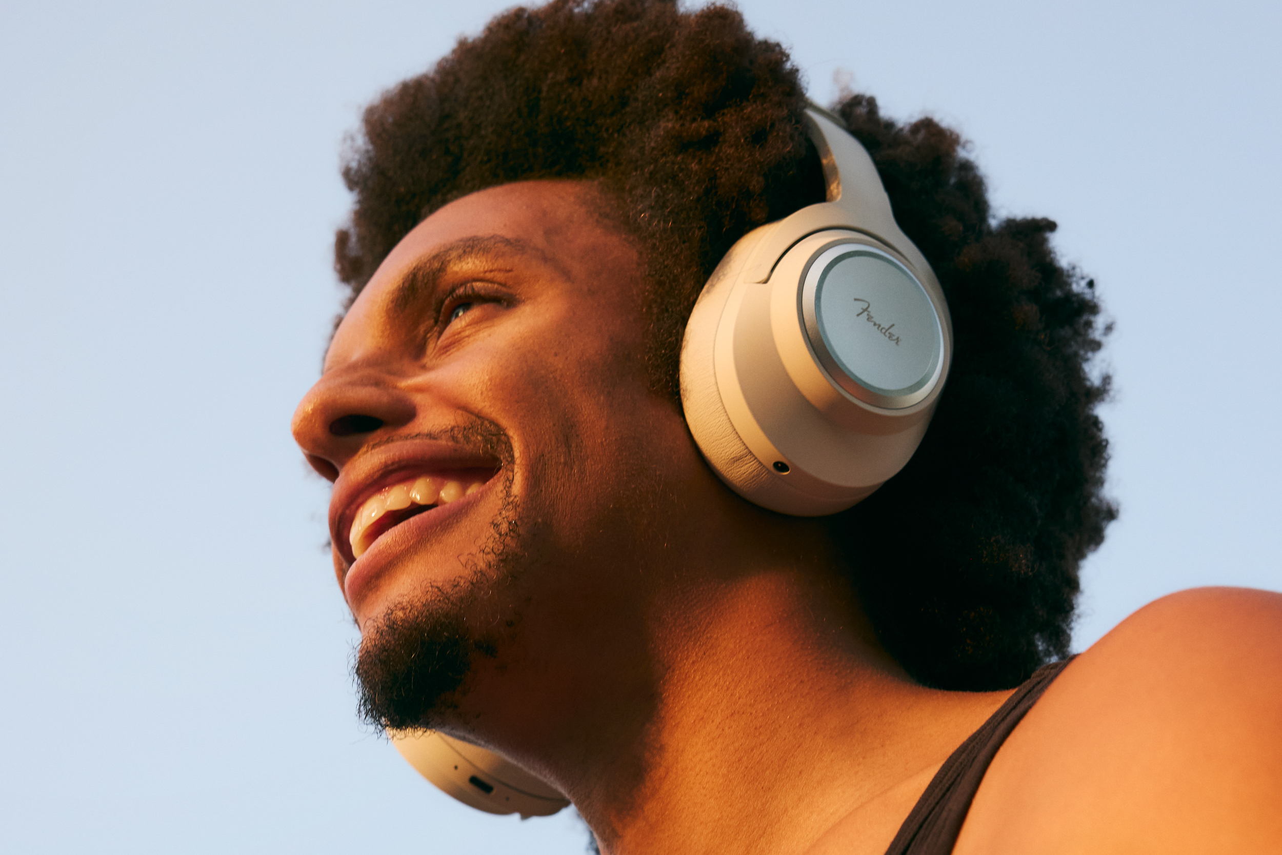 A person smiling while wearing the olympic white version of the Fender Mix wireless headphones.
