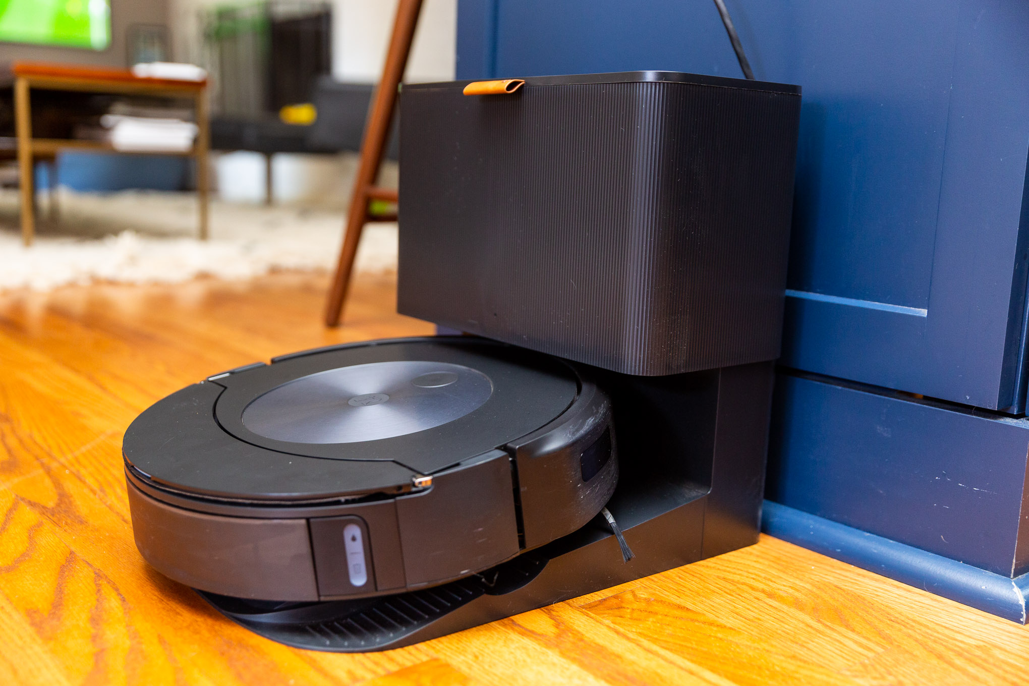 A Roomba vacuum on its docking station in an open-plan kitchen living room.