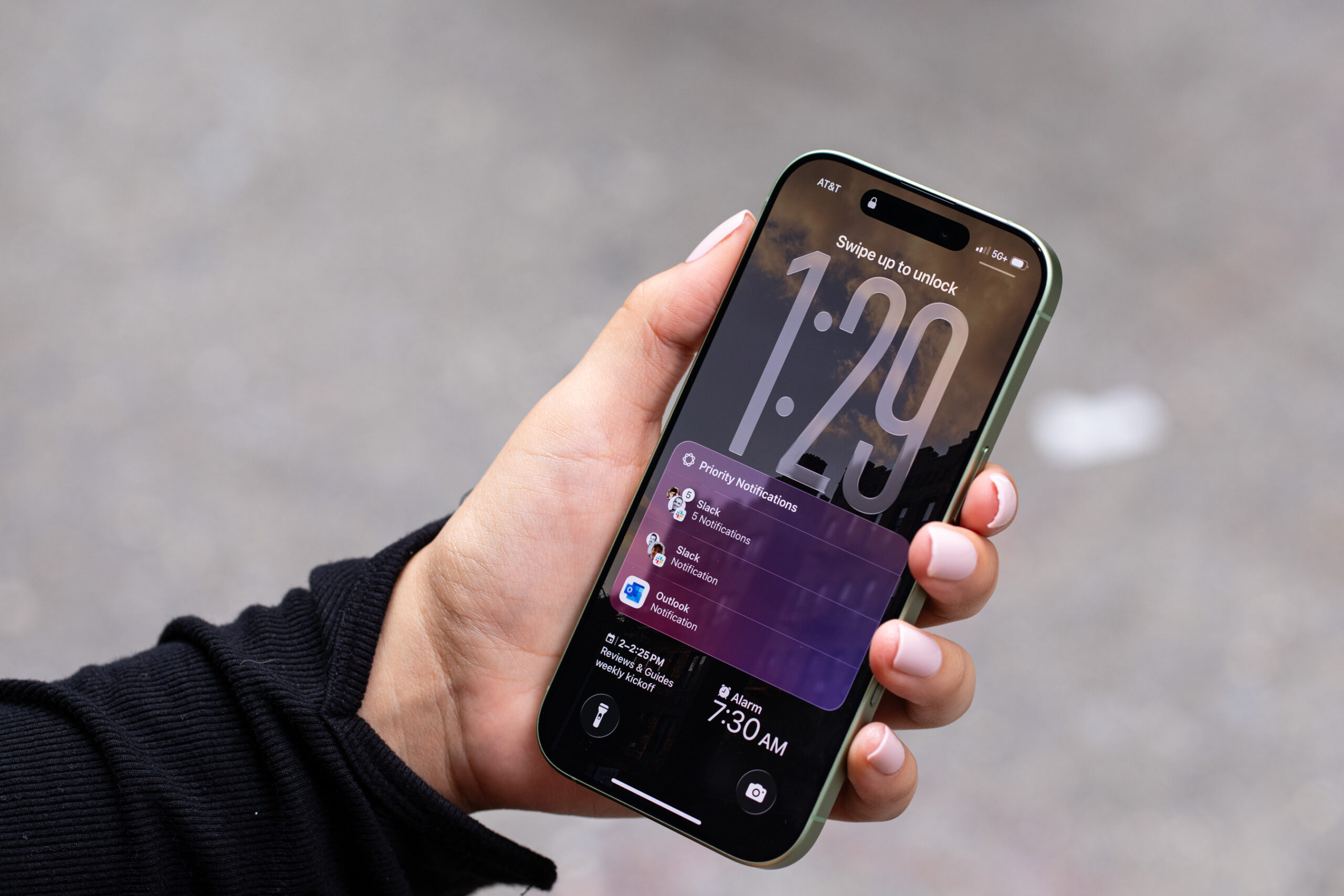 An iPhone 17 held up showing a lock screen with notifications