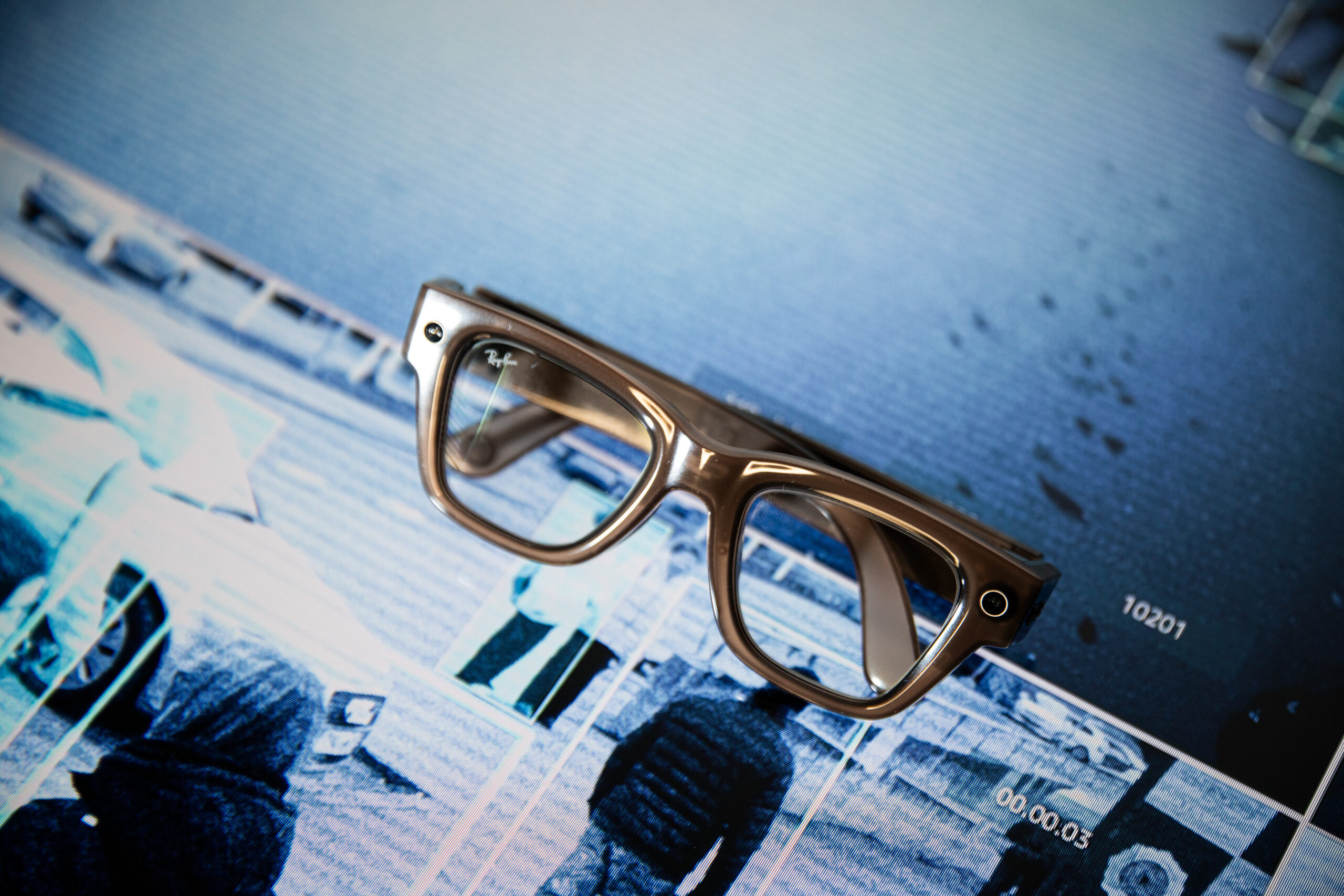 Meta Ray-Ban Display glasses sitting on top of a background showing CCTV footage