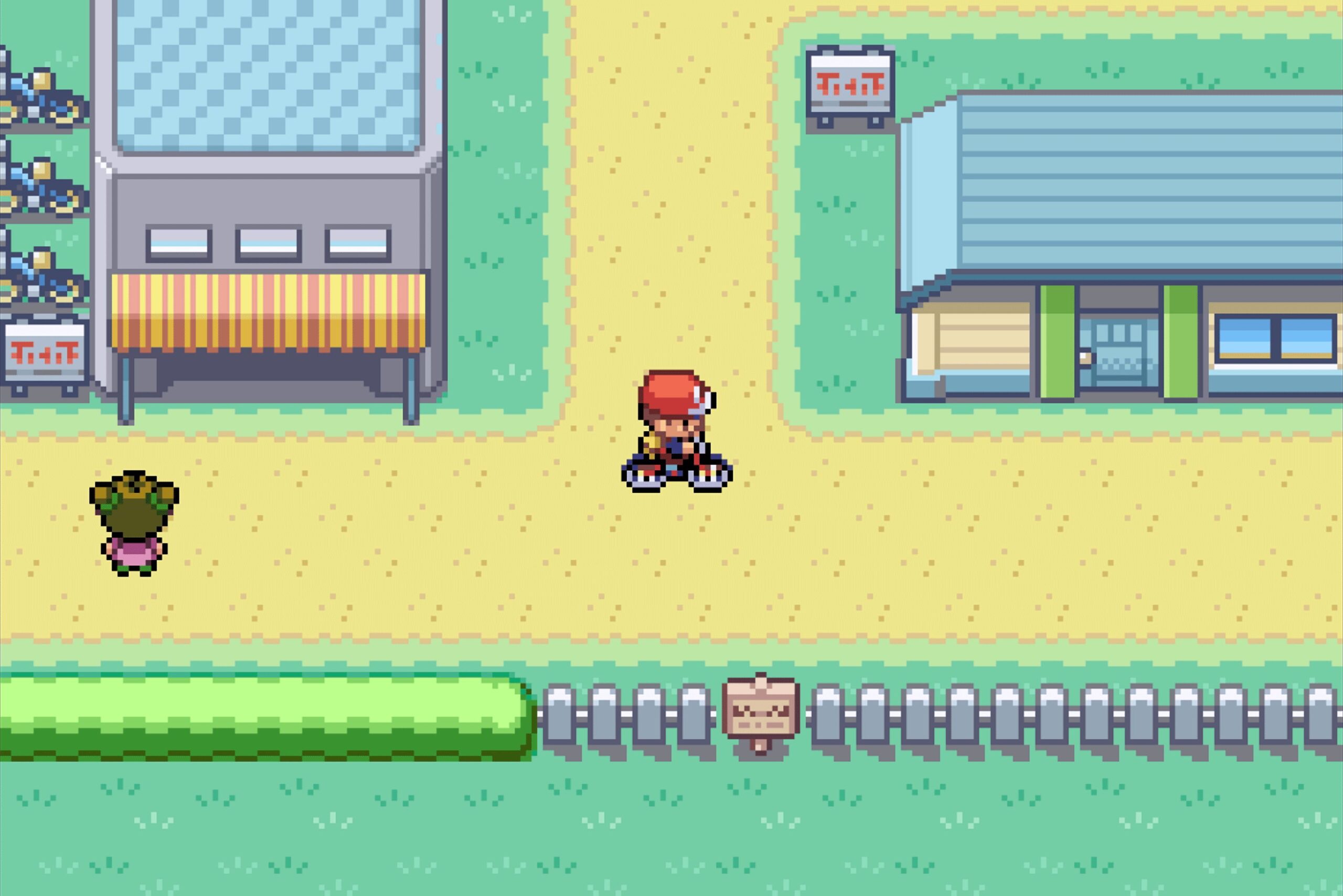 A Pokémon FireRed/LeafGreen screenshot depicting a trainer riding a bicycle through a town.