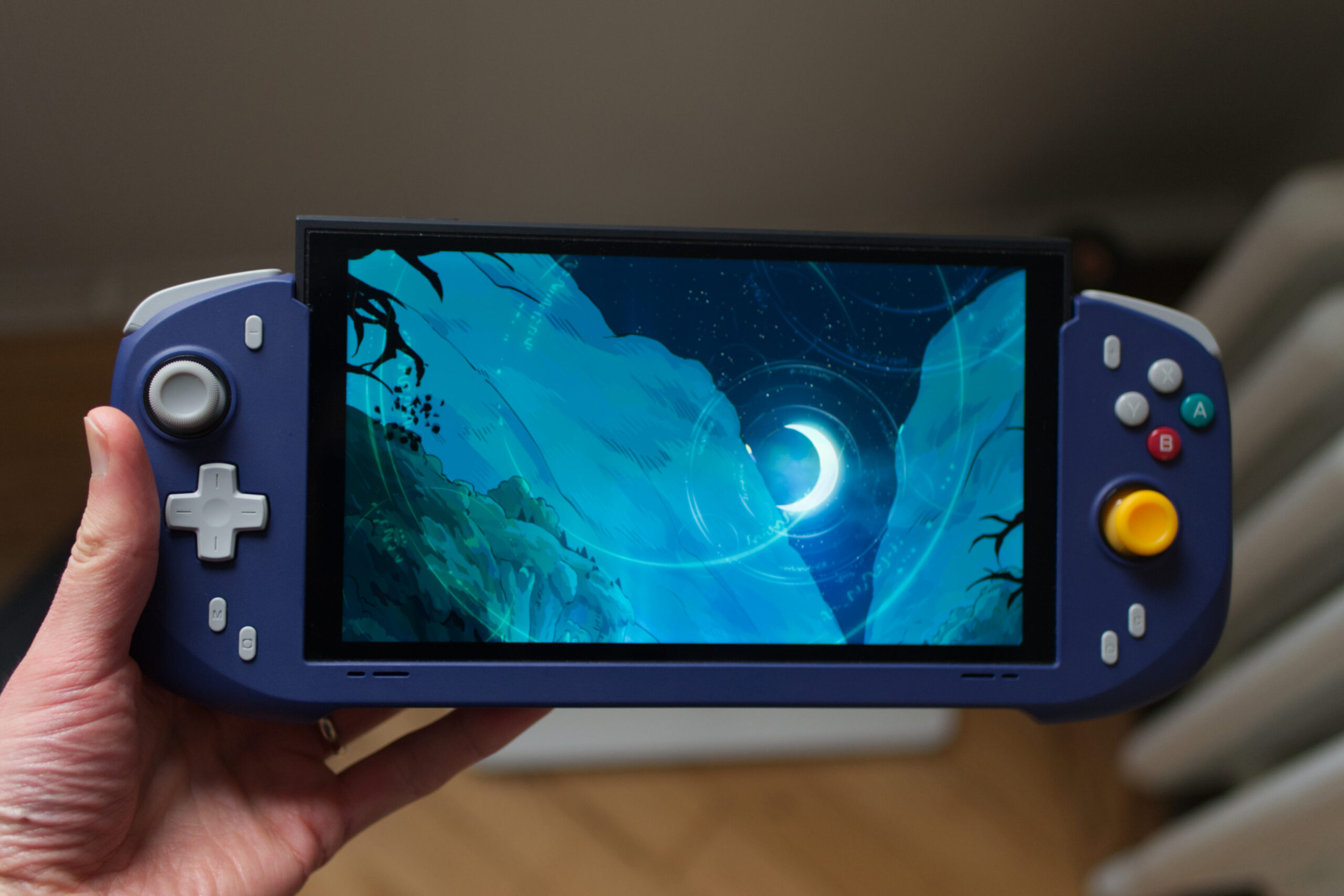 The Abxylute N6 controller with a Switch 2 docked into it. The console is showing Hades 2 on its screen, specifically of a scene showing a gorgeous vista including the moon.