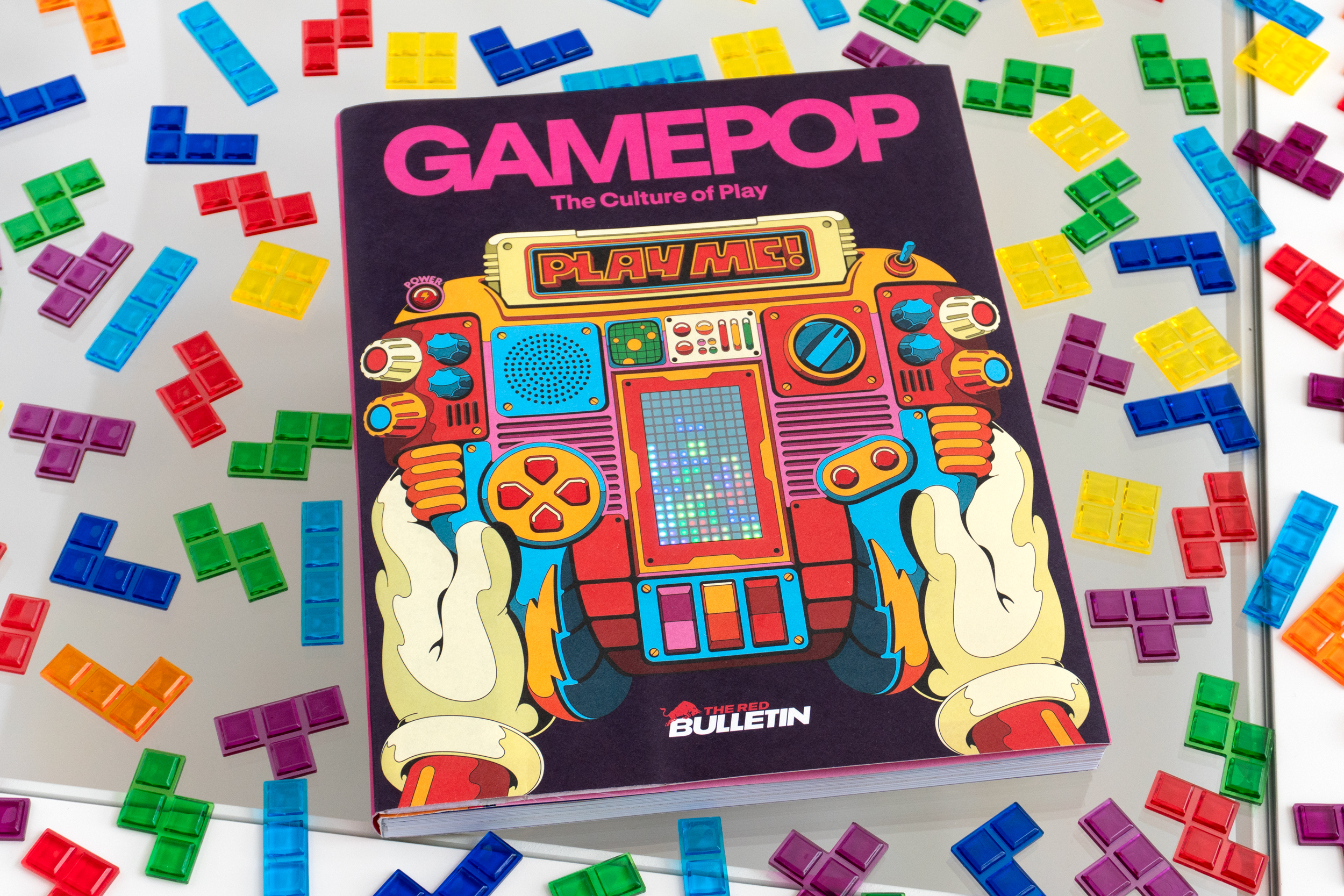 The Red Bull GamePop magazine sitting on a small table covered in plastic Tetris pieces.