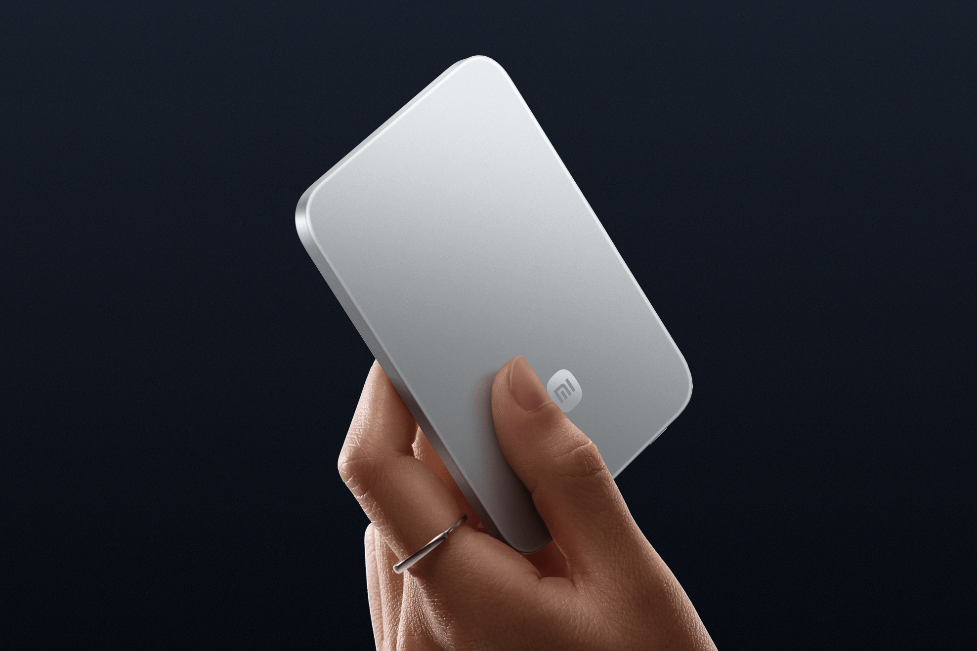 A hand holds the silver version of the Xiaomi UltraThin Magnetic Power Bank 5000.