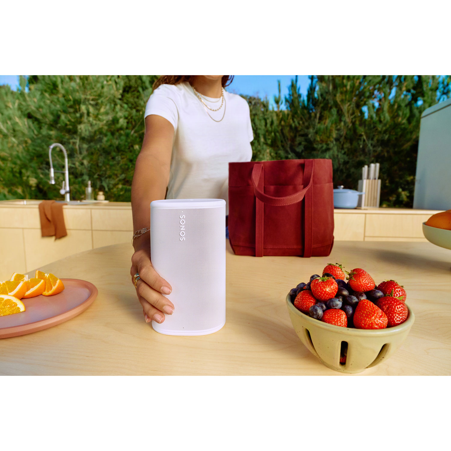 Sonos Play speaker lifestyle image with a person holding it in what appears to be a fully functional outdoor kitchen.